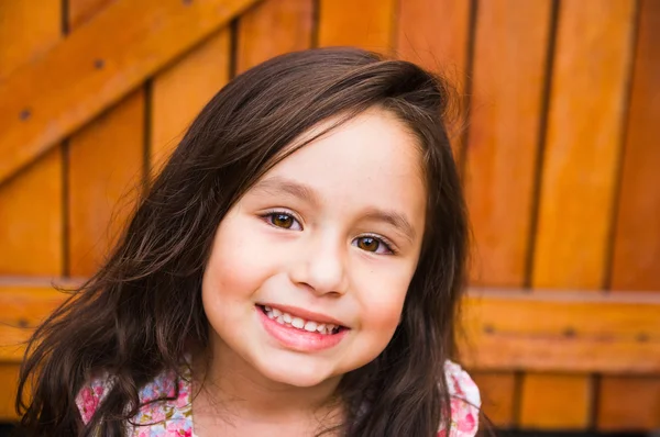 Gorgeous young brunette girl closeup headshot posing for camera, wooden door background — Stockfoto