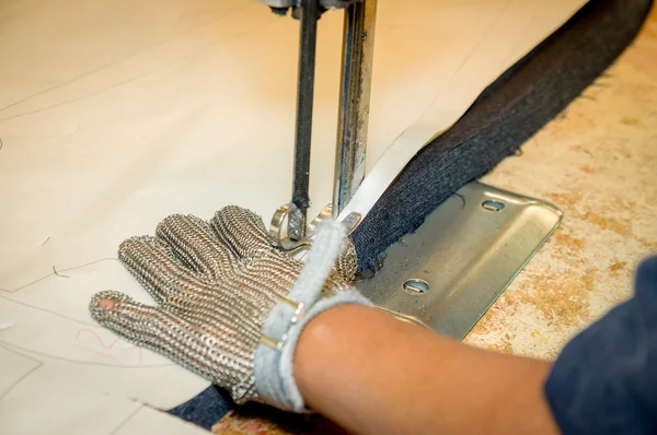 Mãos usando luvas de proteção usando máquina industrial para cortar tapetes, têxteis e outros tecidos pesados — Fotografia de Stock