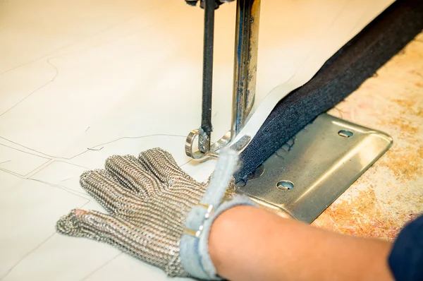 Mãos usando luvas de proteção usando máquina industrial para cortar tapetes, têxteis e outros tecidos pesados — Fotografia de Stock