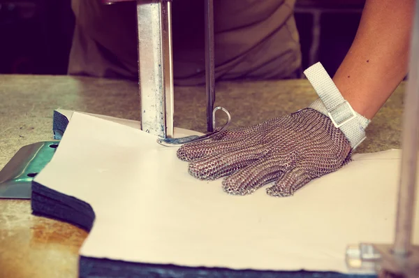 Händer bär skyddshandskar använder industriella maskin för kapning mattor, textilier och andra tunga tyger — Stockfoto