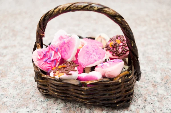 Beautiful basket typical curved handle sitting on granite surface filled with delicious cookies mostly pink colored — Stock Photo, Image