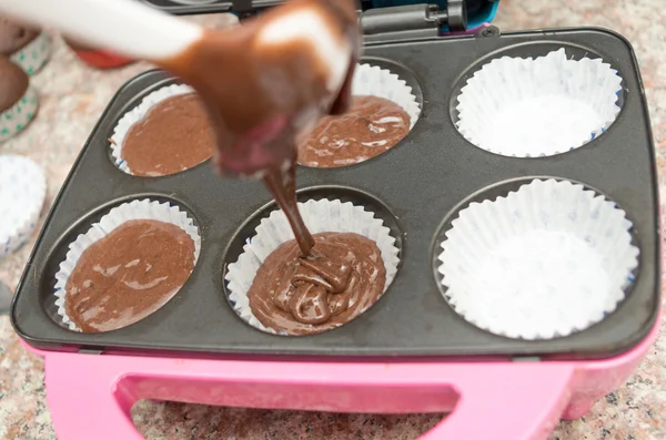 Наличие смеси шоколадных кексов в формованной металлической сковороде, которая может испечь до шести кексов — стоковое фото