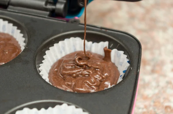 Pouring chocolate cupcake mixture into molded metal pan which can bake up to six cupcakes — Stock Photo, Image