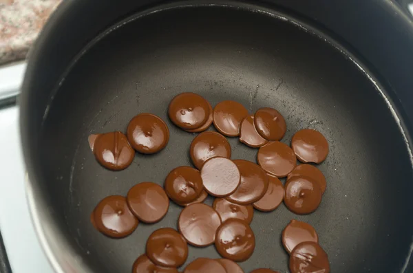 Delicate setup of melting thin circular chocolate pieces in frying pan , shot from above — Stock Photo, Image