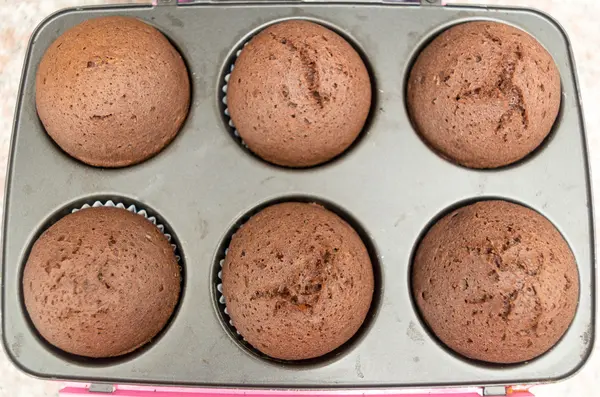 Läckra färska choklad muffins direkt ur ugnen fortfarande sitter inne i metall pan, skott från ovan — Stockfoto