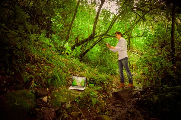 Junger gutaussehender Mann mit Tablet und Laptop mit toller Internetverbindung im Dschungel — Stockfoto