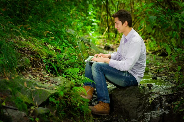 Junger gutaussehender Mann mit Laptop und Internetanschluss im Dschungel — Stockfoto