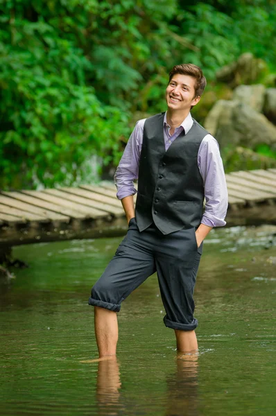 Elegant young man enjoying the nature with his feet inside a lake — Stock Photo, Image