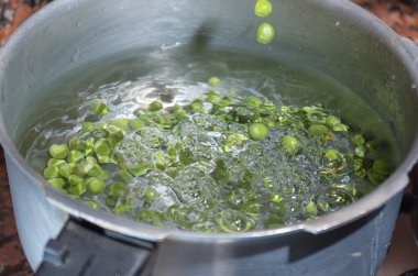 Gümüş renkli metal tencerede yemek yeşil bezelye. fanesca hazırlık kavramı