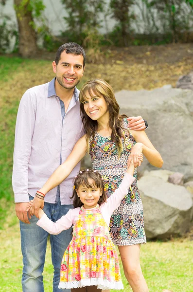 Adorable familia hispana de tres posando en un jardín sonriendo felizmente a la cámara —  Fotos de Stock