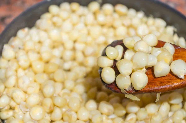 Closeup pot full of cooked corn with wooden spoon scooping up some corns — 图库照片