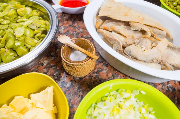 Bowls of different ingredients spread out on granite surface including green peas, onions, abbas, corn, fish, lupini and red beans — Stock Photo, Image