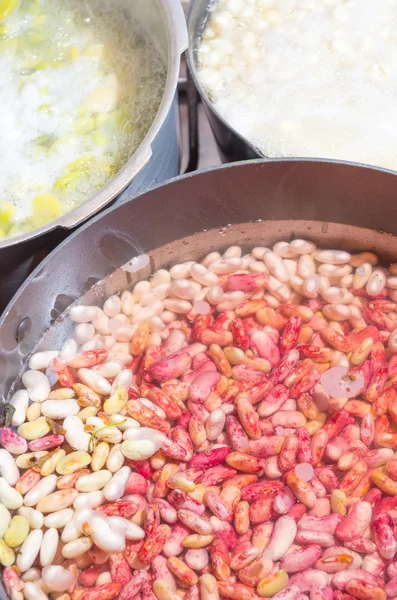 Black cooking pot of white and red beans drained in water with some other pots around, preparation fanesca concept — Stock Image Black cooking pot of white and red beans drained in water with some other pots around, preparation fanesca concept Stock Image