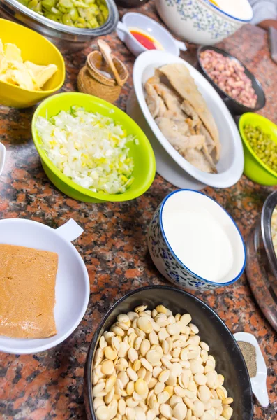 Bowls of different ingredients spread out on granite surface including green peas, onions, abbas, corn, fish, lupini and red beans — Stock Image Bowls of different ingredients spread out on granite surface including green peas, onions, abbas, corn, fish, lupini and red beans Stock Image