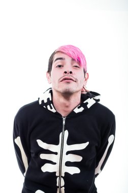 Hispanic young adult with pink hair and black skeleton hoodie posing for camera standing holding arms behind back