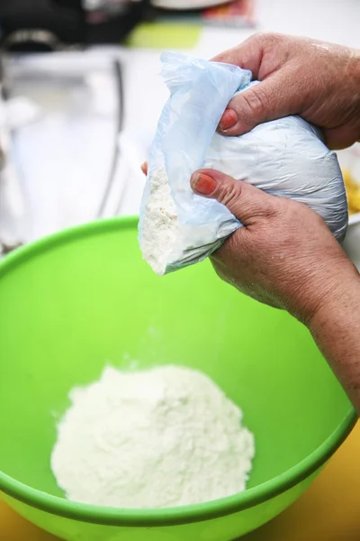 Two hands holding bag of flour while puring into green plastic bowl, preparing fanesca concept — Φωτογραφία Αρχείου