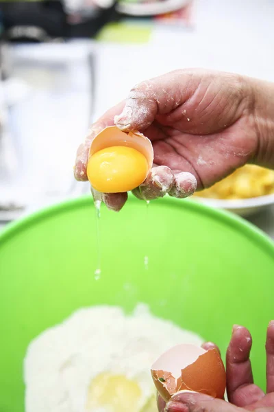 Deux mains séparant blanc d'oeuf du jaune sur un bol de farine en plastique vert, préparant le concept de fanesca — Photo