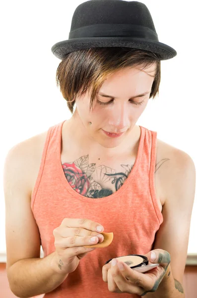 Headshot young hispanic male wearing black hat, red sleveless shirt with tattoos on chest and arms, punk rock insipired look, looking at his cellphone — Stockfoto