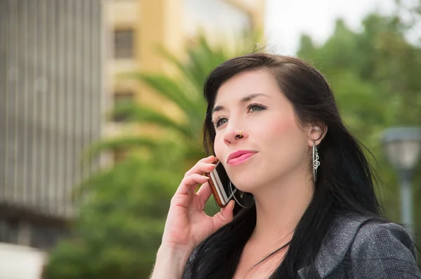 Elegante modelo latina con ropa casual inteligente caminando en la calle urbana hablando por su teléfono móvil — Foto de Stock