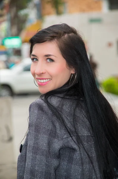 Classy latina model wearing smart casual clothes walking in urban street looking backwards towards camera smiling — Stok fotoğraf