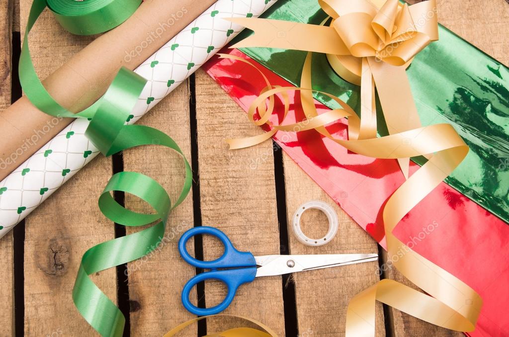 Gift wrapping concept with various paper colors, scissors, tape and other  decoratives lying on wooden surface Stock Photo by ©pxhidalgo 87326906