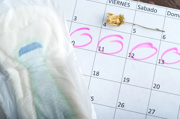 ピンクと白のカレンダーが回ります月経期間ときれいなタンポンの上に横になっています。 — ストック写真