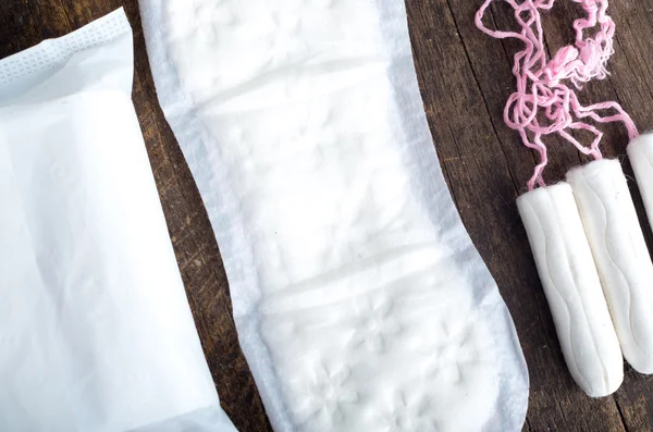 Sanitary pads for women with clean white tampons lying on top of wooden surface, shot from above angle — 图库照片