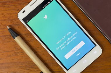 QUITO, ECUADOR - AUGUST 3, 2015: White smartphone lying on desk with Twitter screen open next to a pen, business and communication concept