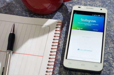 Quito, Ekvator - 3 Ağustos 2015: Instagram oturum açma Web sitesi ekran tabloyla bir kalem yanındaki açık not defteri ve kahve kupa, iletişim iş kavramı yatan beyaz smartphone
