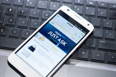 QUITO, ECUADOR - AUGUST 3, 2015: White smartphone closeup lying on laptop keyboard with Amazon website screen visible