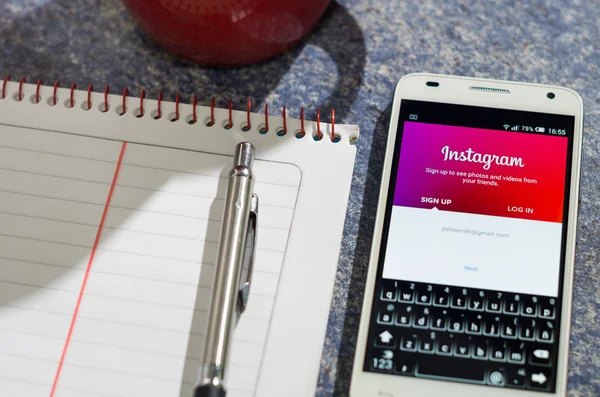 QUITO, ECUADOR - AUGUST 3, 2015: White smartphone lying on table with Instagram website screen open next to a pen, notepad and coffee mug, business communication concept — 图库照片