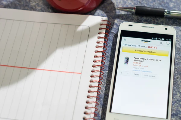 QUITO, ECUADOR - 3 DE AGOSTO DE 2015: Smartphone blanco en la mesa con la pantalla del sitio web de Amazon abierta junto a un bolígrafo, bloc de notas y taza de café, concepto de comunicación empresarial —  Fotos de Stock
