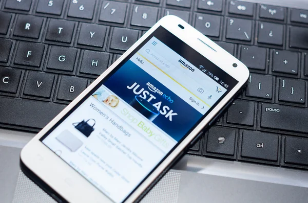 QUITO, ECUADOR - AUGUST 3, 2015: White smartphone closeup lying on laptop keyboard with Amazon website screen visible — ストック写真