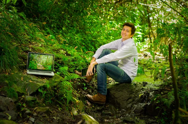 Mladý pohledný muž, práci s notebookem a relaxaci v džungli — Stock fotografie