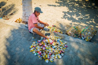 Man recycling empty cans in the street, Colombia clipart