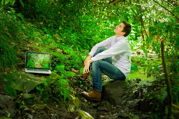 Joven hombre guapo que trabaja con el ordenador portátil y relajarse en la selva —  Fotos de Stock