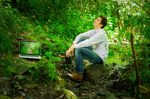 Joven hombre guapo que trabaja con el ordenador portátil y relajarse en la selva —  Fotos de Stock