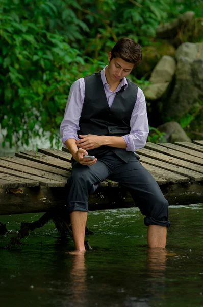 Jovem usando telefone celular na floresta do lago — Fotografia de Stock