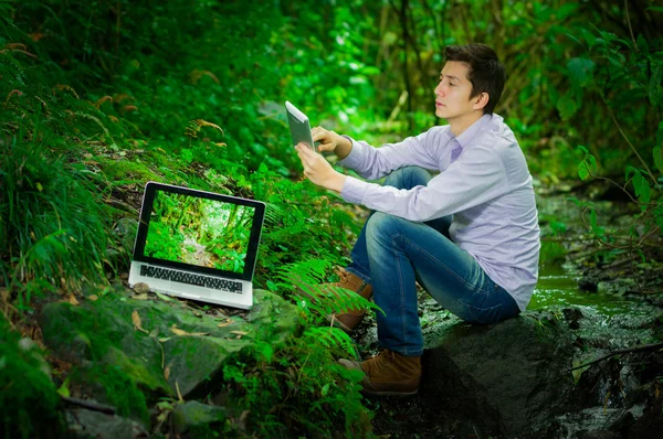 ジャングル森林で偉大なインターネット接続を持つ若いハンサムな男 — ストック写真