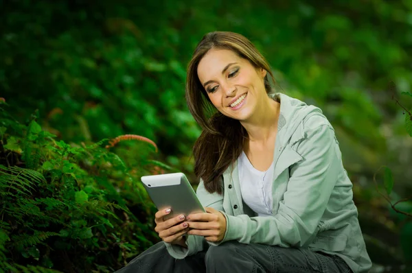 Krásná mladá dívka drží tablet těší vynikající konektivitu v džungli — Stock fotografie