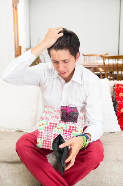 Ung snygg orolig man håller julklappar och sin plånbok — Stockfoto