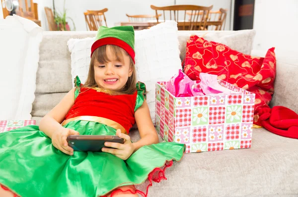 Menina vestida como duende de Natal segurando telefone celular — Fotografia de Stock