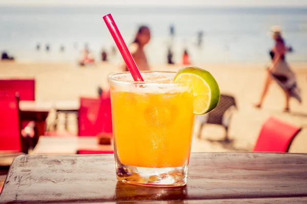 Delicioso refrescante cóctel amarillo con playa al fondo —  Fotos de Stock