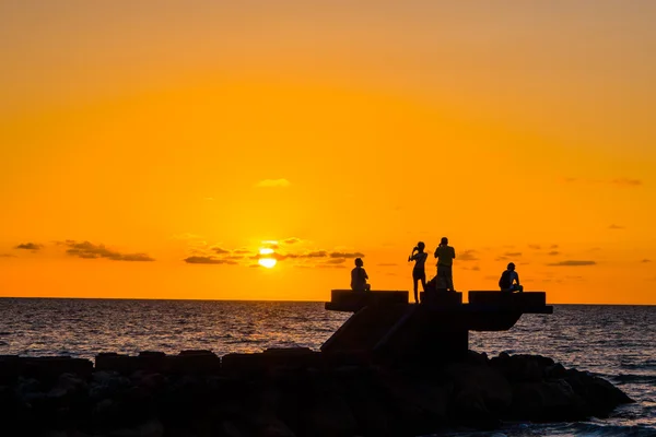 Sillhouette människor på stranden under solnedgången — Stockfoto