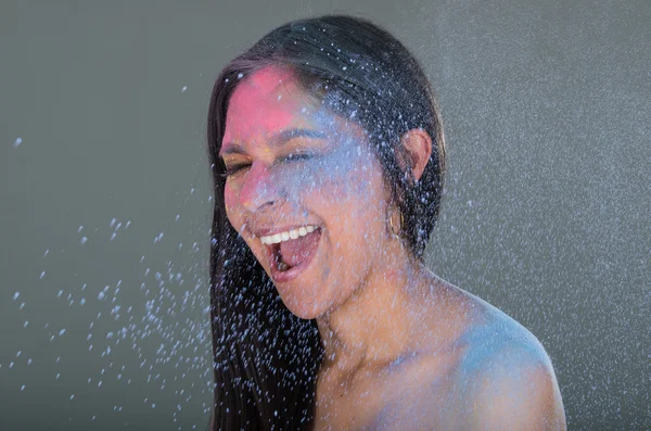 Beautiful young brunette girl with colorful powder blowing in her face — Stock Photo, Image