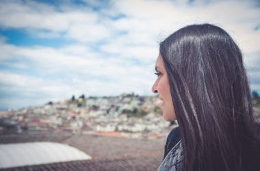 Classy attractive brunette wearing black white dress sitting on rooftop with nice view overlooking city