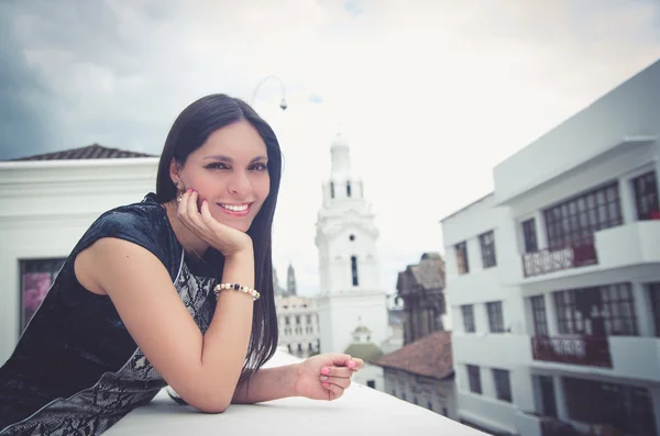 Classy attractive brunette wearing black white dress in urban environment leaning on surface and enjoying a view while smiling — Stok fotoğraf