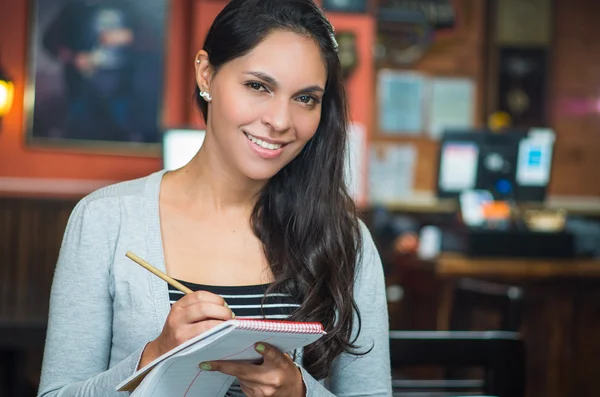 Brunette model serveerster in restaurant neerschrijven van volgorde en lacht om camera — Stockfoto