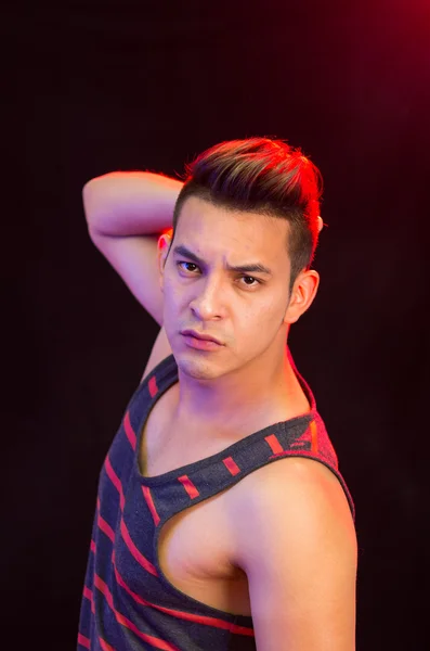 Masculino hispânico vestindo vermelho preto listrado singlet posando com expressão facial grave — Fotografia de Stock