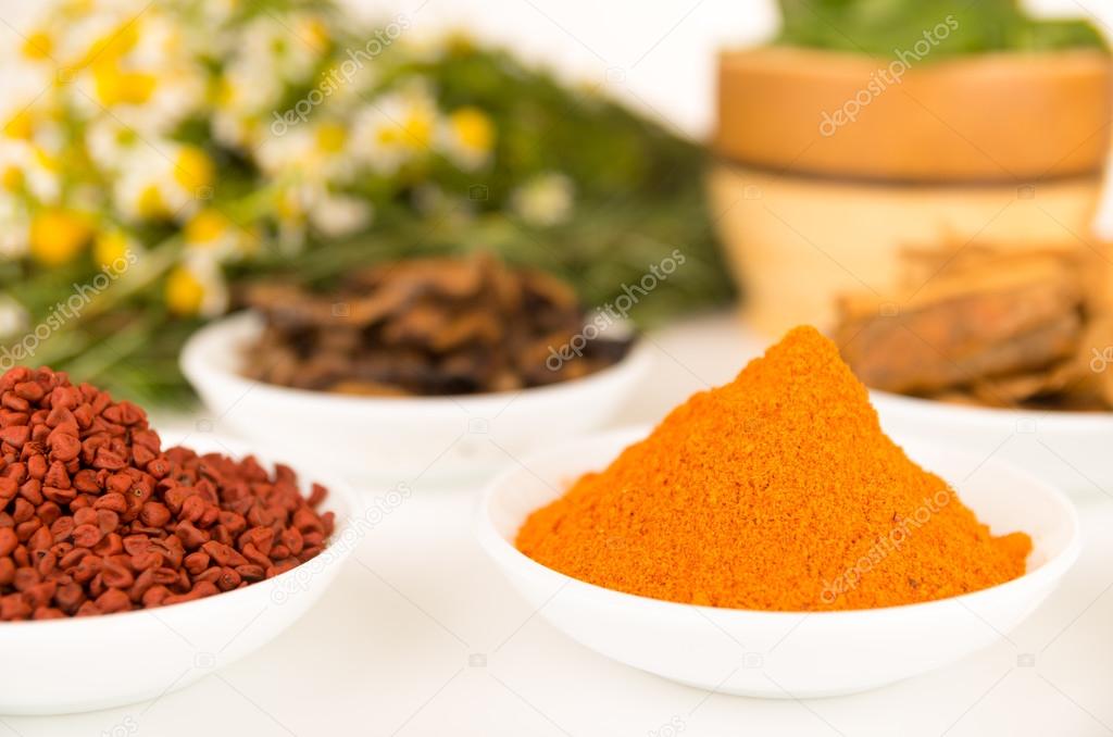 Beautiful colorful display of different spices green orange brown in white bowls, shot from above side angle, bright background